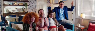 Amigos na sala sentados no sofá celebrando a caixinha Tetra Pak